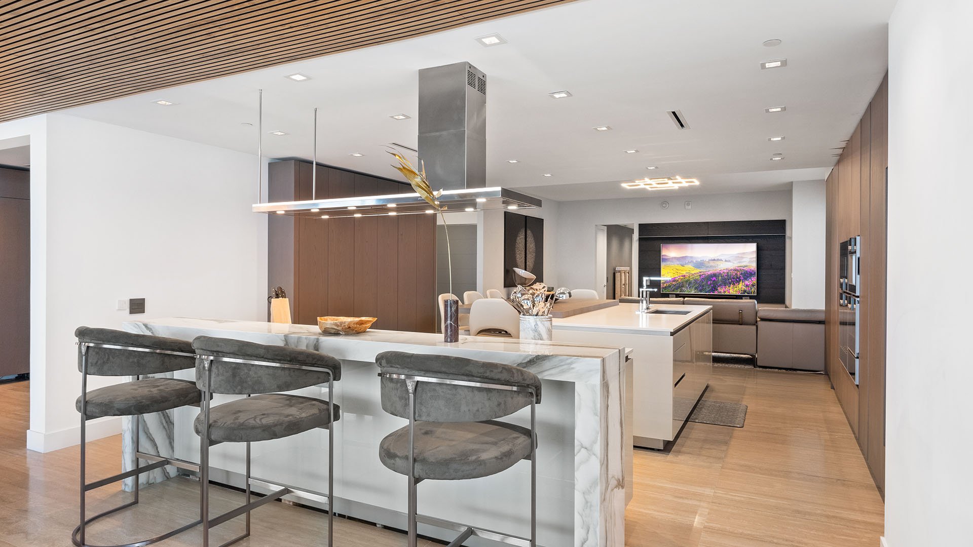 Turnberry Ocean Club in Sunny Isles Beach luxury and ultra luxury condos showcase an open-plan chef kitchen with a waterfall island, bar seating, and warm wood cabinetry.