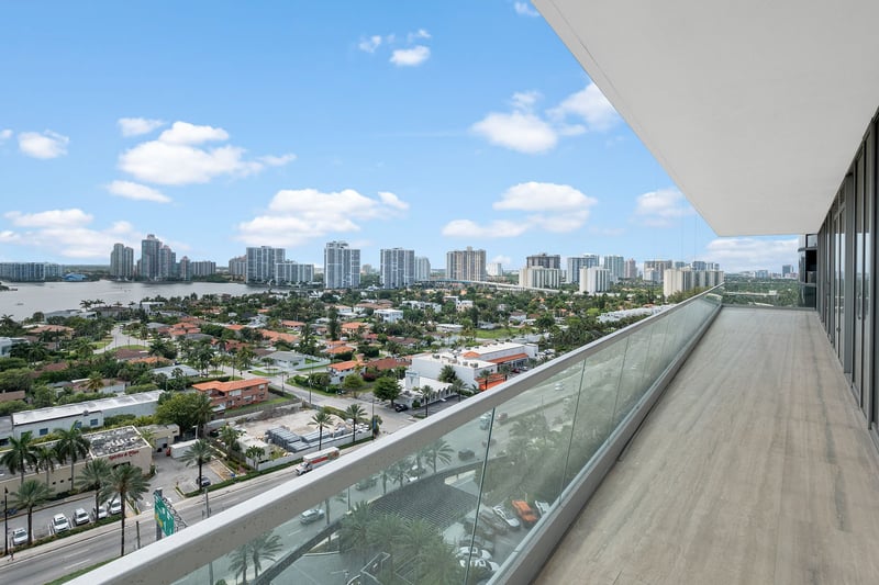 Turnberry Ocean Club in Sunny Isles Beach luxury and ultra luxury condos showcase a long glass balcony with city skyline and bay views under a cantilevered overhang.