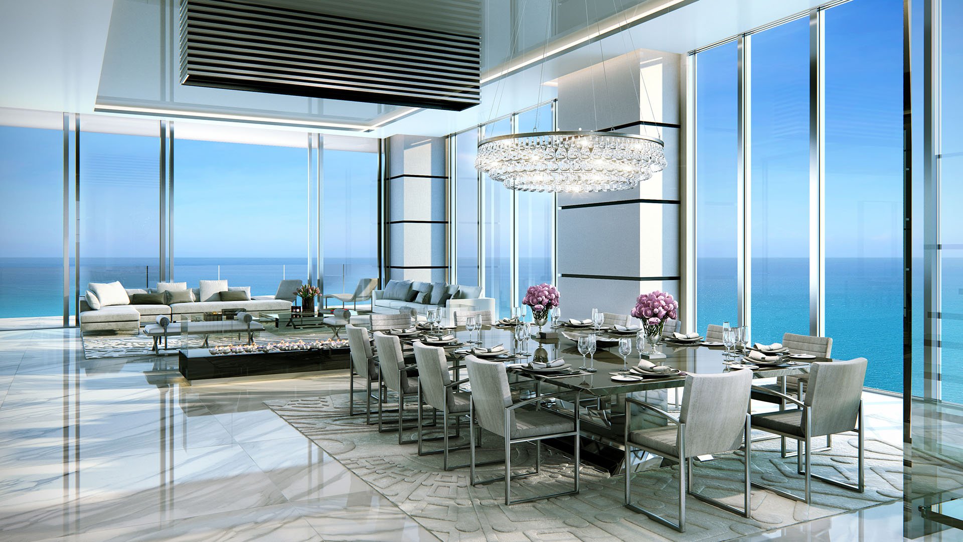 Turnberry Ocean Club in Sunny Isles Beach luxury and ultra luxury condos showcase a living and dining space with a crystal chandelier, marble floors, and an oceanfront glass corner.