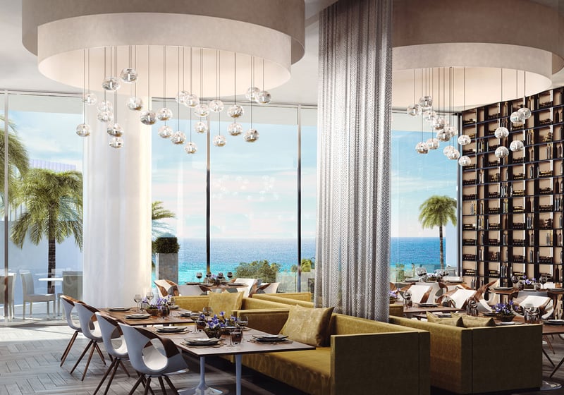 Turnberry Ocean Club in Sunny Isles Beach luxury and ultra luxury condos showcase an oceanfront lobby restaurant with banquettes, pendant lighting, and terrace dining beyond.