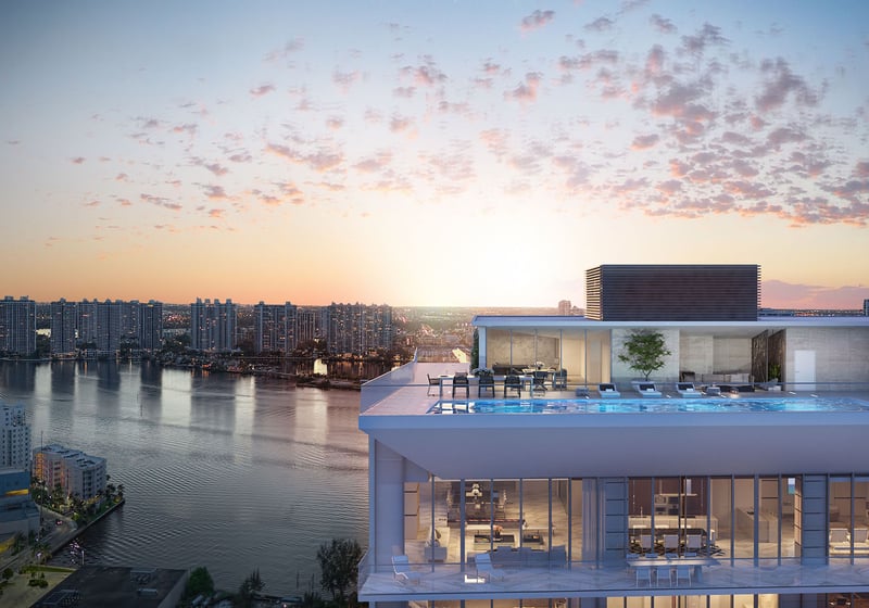 Turnberry Ocean Club in Sunny Isles Beach luxury and ultra luxury condos showcase a rooftop residence aerial with bay water, glowing interiors, and a sunset sky.