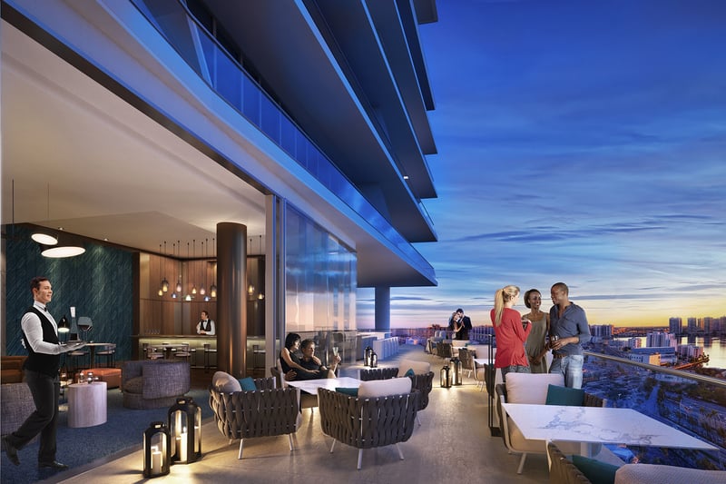 Turnberry Ocean Club in Sunny Isles Beach luxury and ultra luxury condos showcase a sunset lounge terrace with outdoor seating, service staff, and skyline views at dusk.