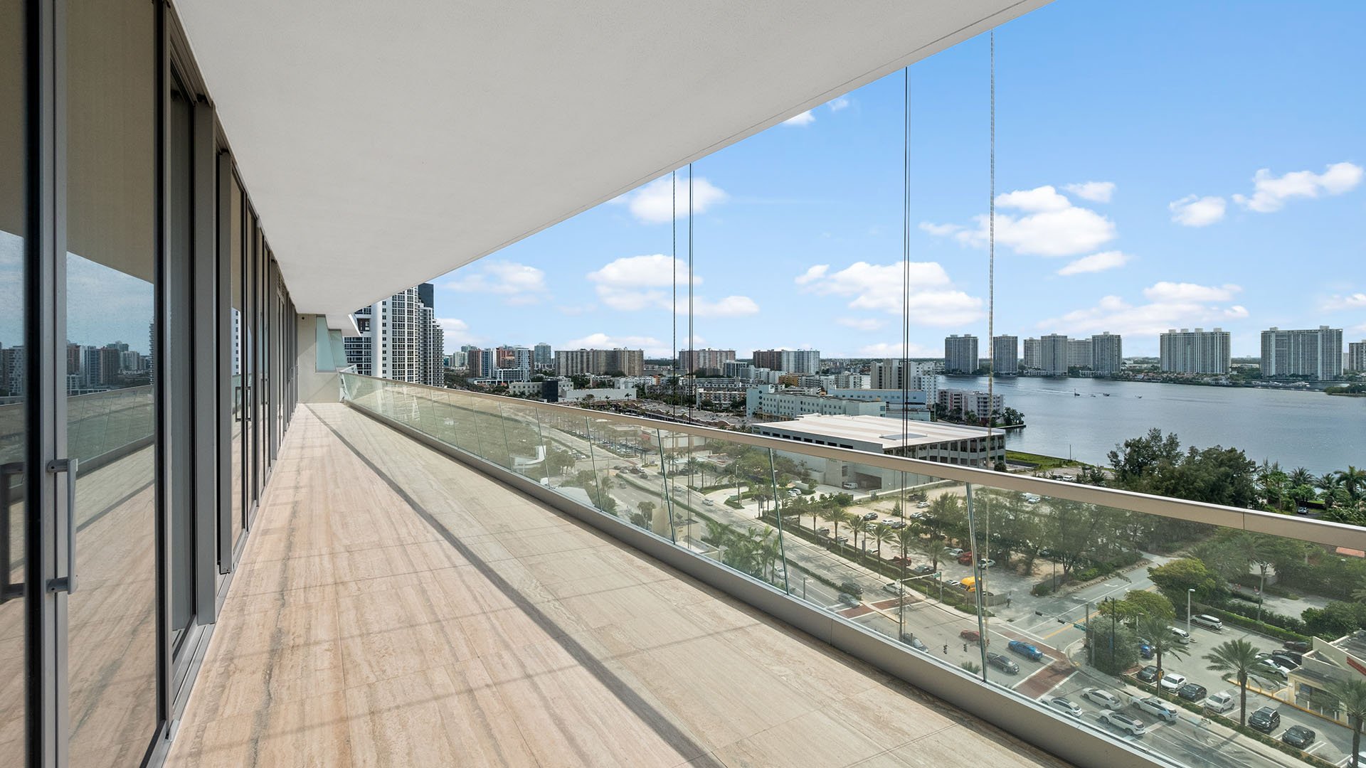 Turnberry Ocean Club in Sunny Isles Beach luxury and ultra luxury condos showcase a wraparound balcony with glass railings overlooking the Intracoastal waterway and skyline.