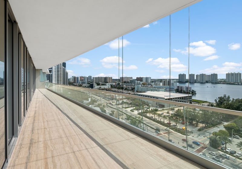 Turnberry Ocean Club in Sunny Isles Beach luxury and ultra luxury condos showcase a wraparound balcony with glass railings overlooking the Intracoastal waterway and skyline.