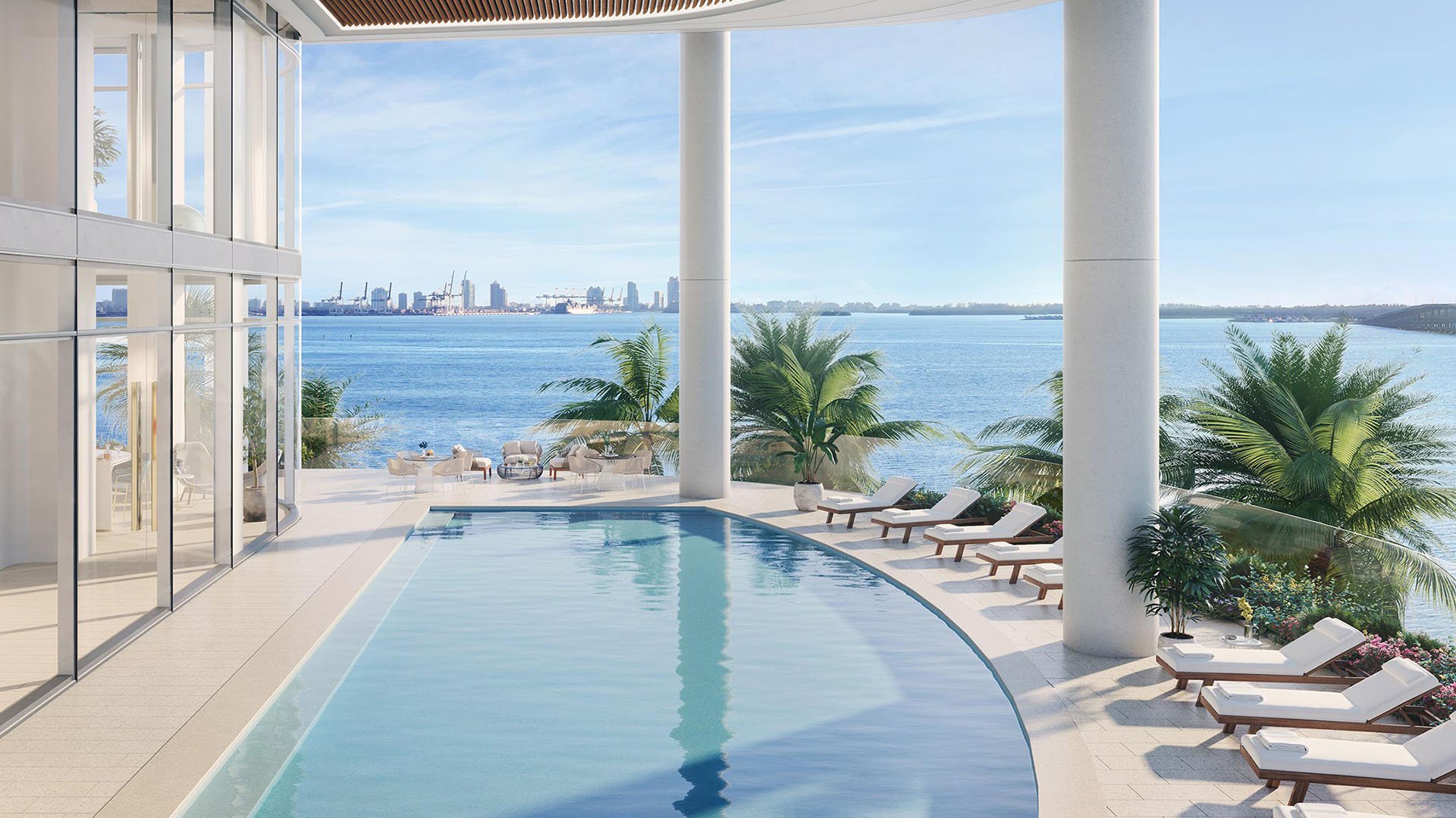 Una Residences Brickell, Miami waterfront lap pool with sun loungers, modern columns and Biscayne Bay panorama, showcasing luxury and ultra luxury preconstruction condos resort amenities in Brickell.