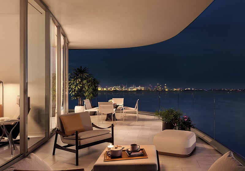 Una Residences Brickell, Miami private terrace at night with outdoor lounge and dining, glass railing and waterfront city lights, enhancing luxury and ultra luxury preconstruction condos with indoor-outdoor living.