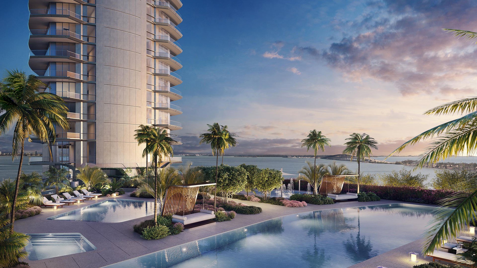 Una Residences Brickell, Miami resort-style pool deck with multiple pools, cabanas and palm landscaping overlooking Biscayne Bay, defining luxury and ultra luxury preconstruction condos amenities at sunset.