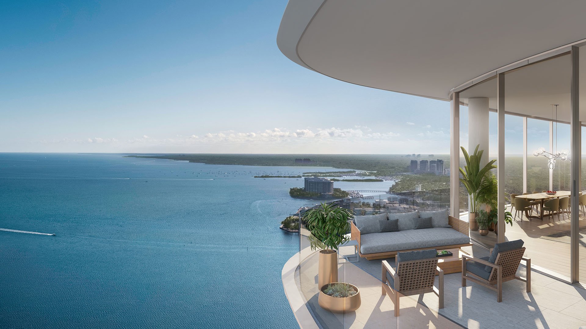 Una Residences Brickell, Miami south terrace private balcony with outdoor lounge seating and panoramic Biscayne Bay views, highlighting luxury and ultra luxury preconstruction condos with curved glass and expansive sky.