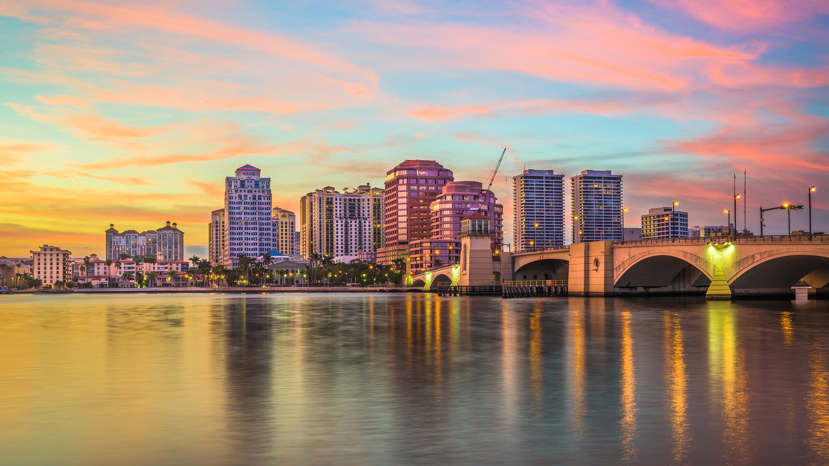 West Palm Beach sunset cityscape over the Intracoastal, pastel clouds and towers, destination for luxury and ultra luxury condos; preconstruction and resale. Featuring waterfront.