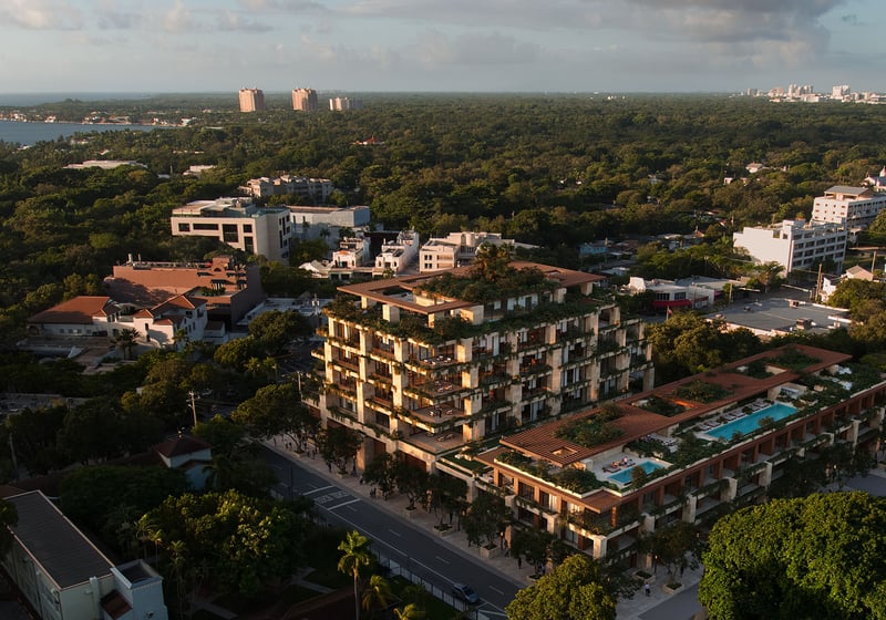 Aerial sunset view of Ziggurat in Coconut Grove, Miami, Florida, with lush green terraces and a rooftop pool, showcasing luxury amenities and ultra luxury preconstruction condos near Biscayne Bay.