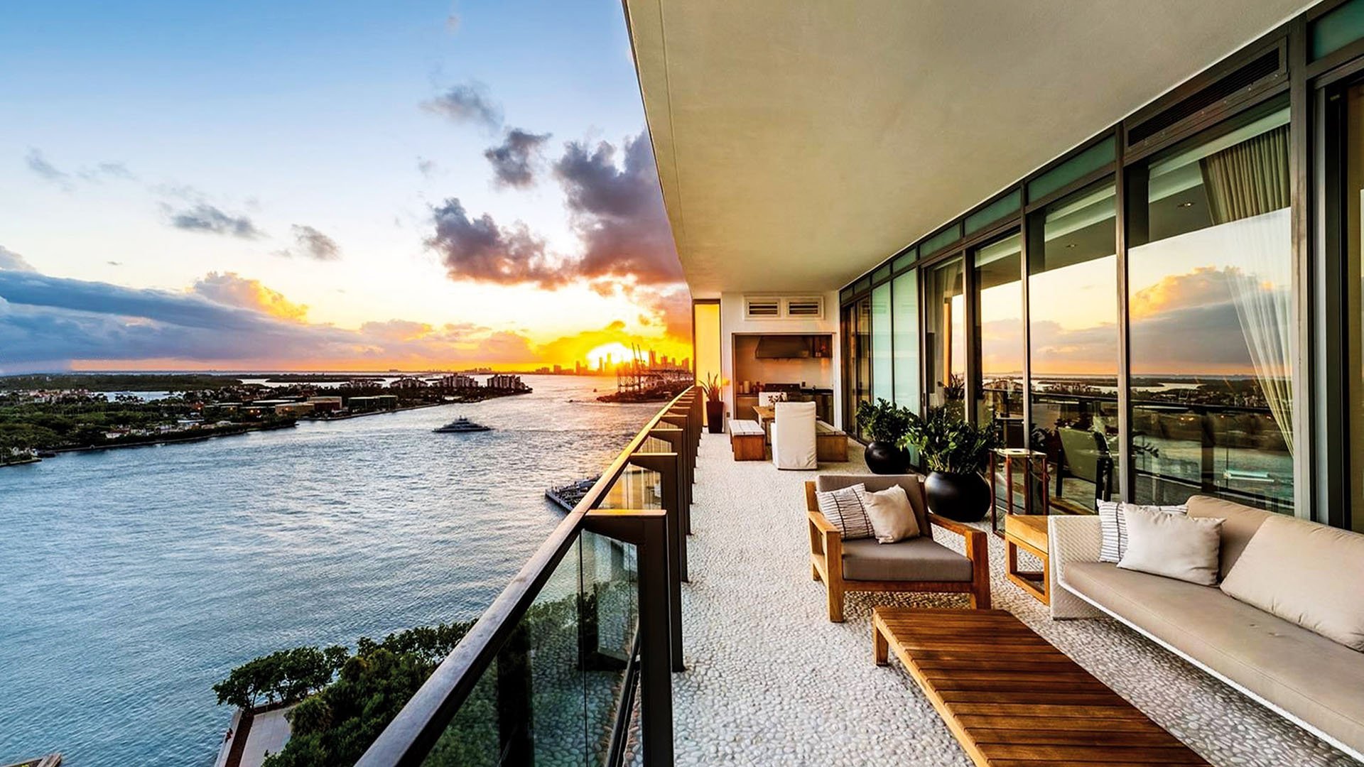 Sunset waterfront terrace with lounge seating and an outdoor kitchen at Apogee in South Beach, highlighting luxury and ultra luxury condos with expansive bayfront outdoor living.