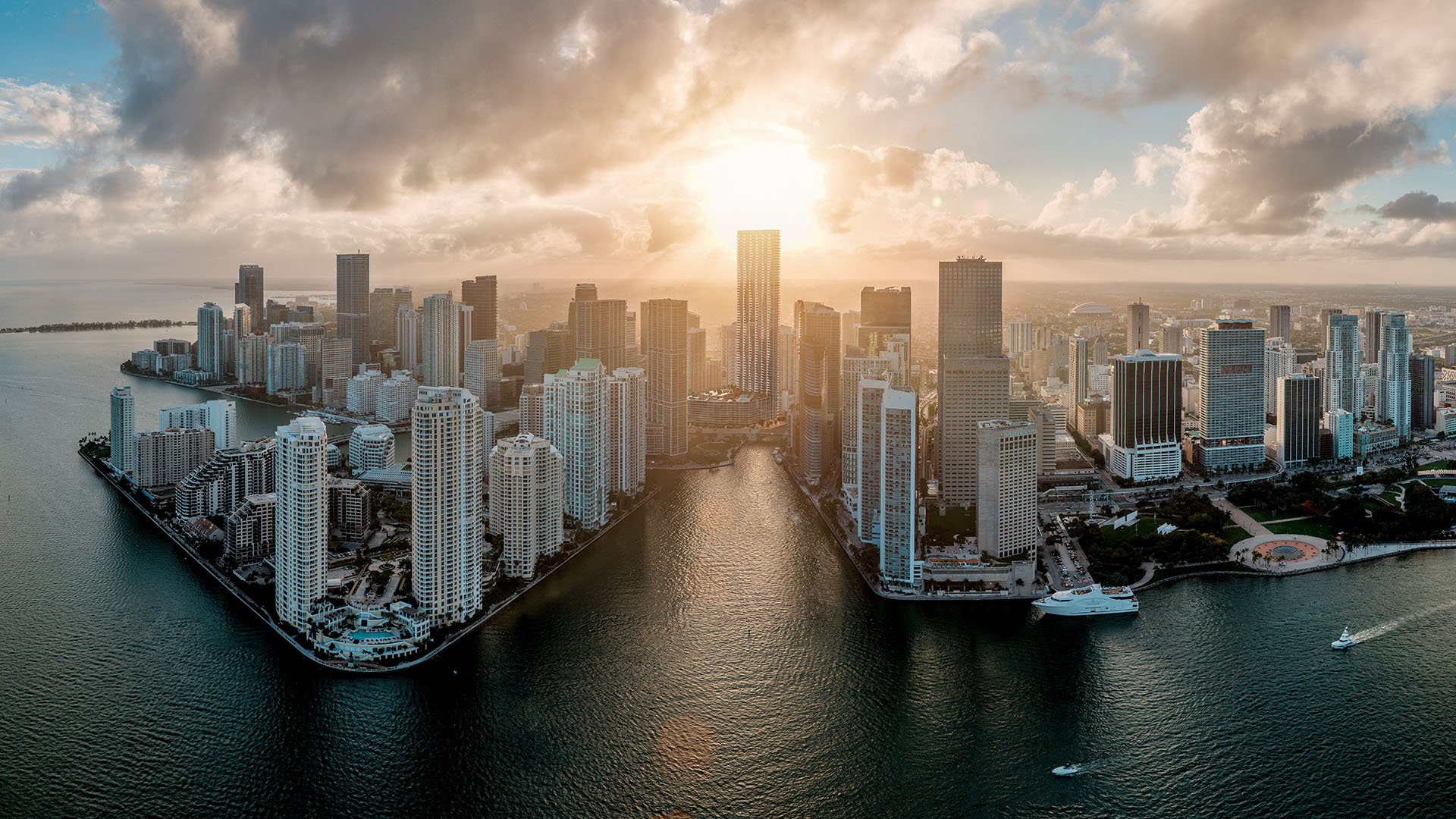 Baccarat Residences in Brickell, Miami, luxury and ultra luxury condos featuring a golden-hour aerial over the waterfront peninsula, bay water, boats, and the downtown skyline.