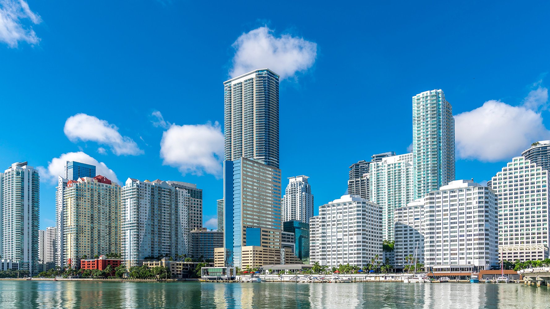 Brickell, Miami waterfront skyline under blue sky, boats and boardwalks—coveted luxury and ultra luxury condos, preconstruction and resale.