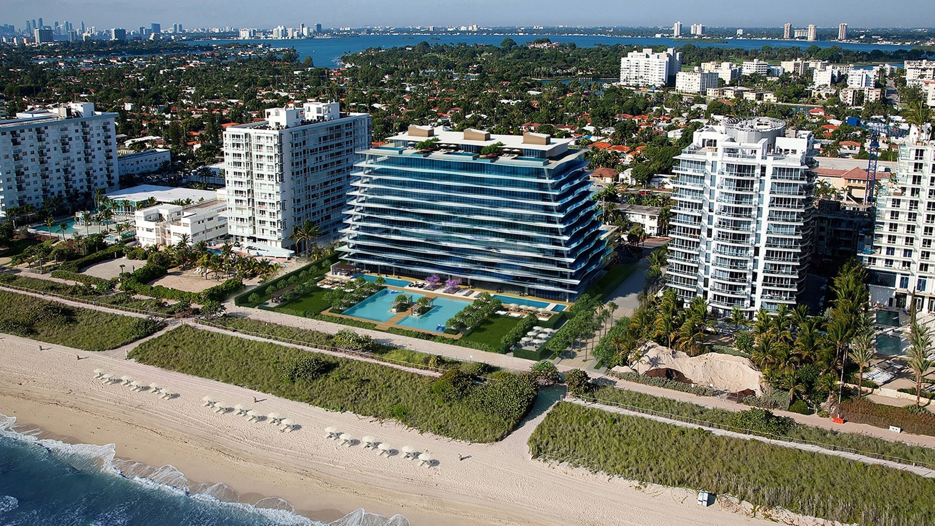 Aerial view of Fendi Chateau Residences in Surfside showing the beachfront tower, landscaped grounds, and pool terrace, showcasing luxury and ultra luxury condos along the shoreline.