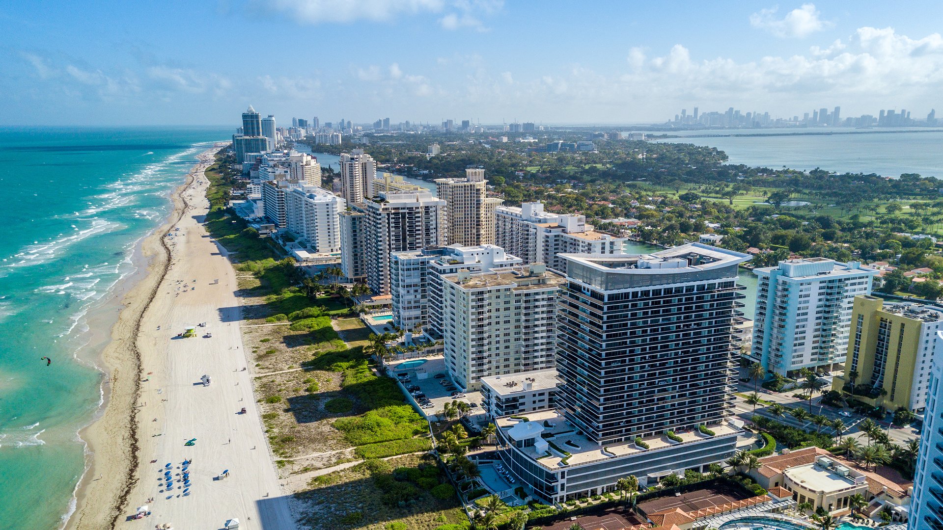 Miami Beach aerial over Atlantic shoreline and Biscayne Bay—resort towers, beaches and canals; top market for luxury and ultra luxury condos, with preconstruction and resale.