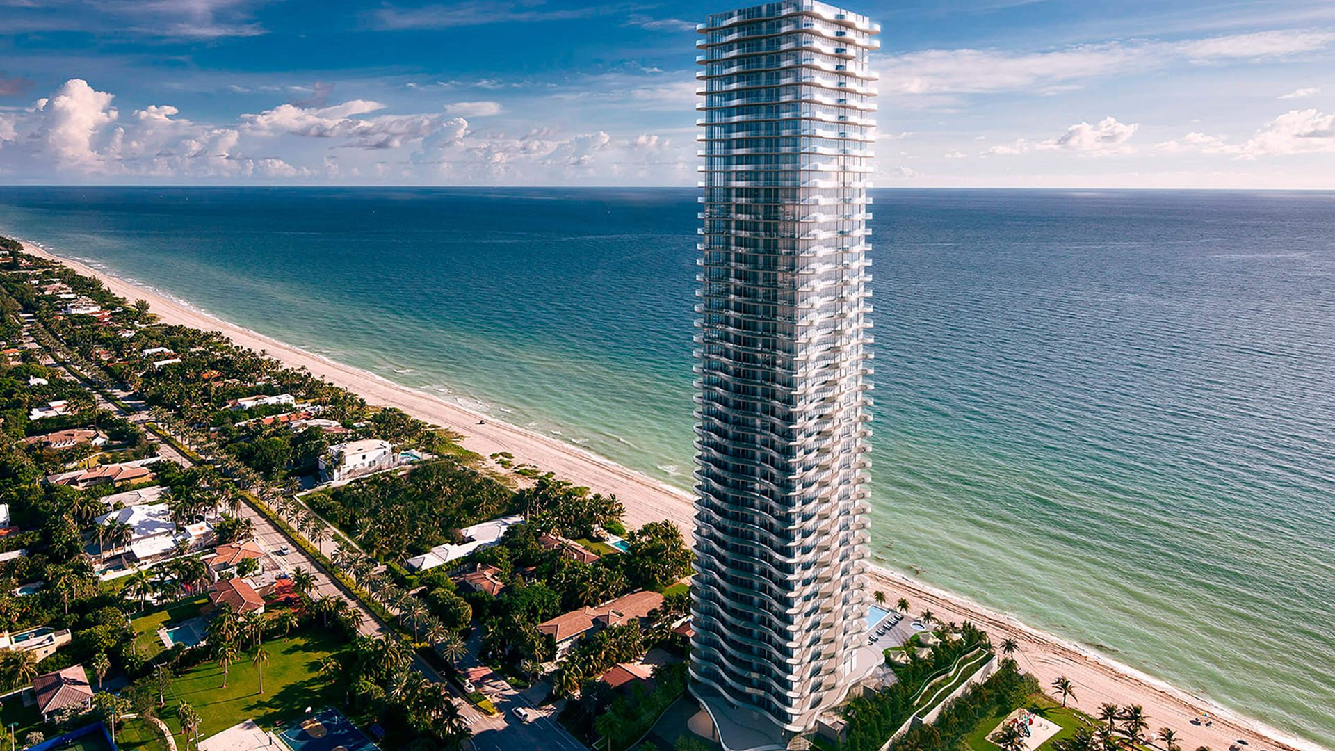 Aerial waterfront view of Regalia in Sunny Isles Beach, where luxury and ultra luxury condos rise beside a long sandy coastline and turquoise ocean water.
