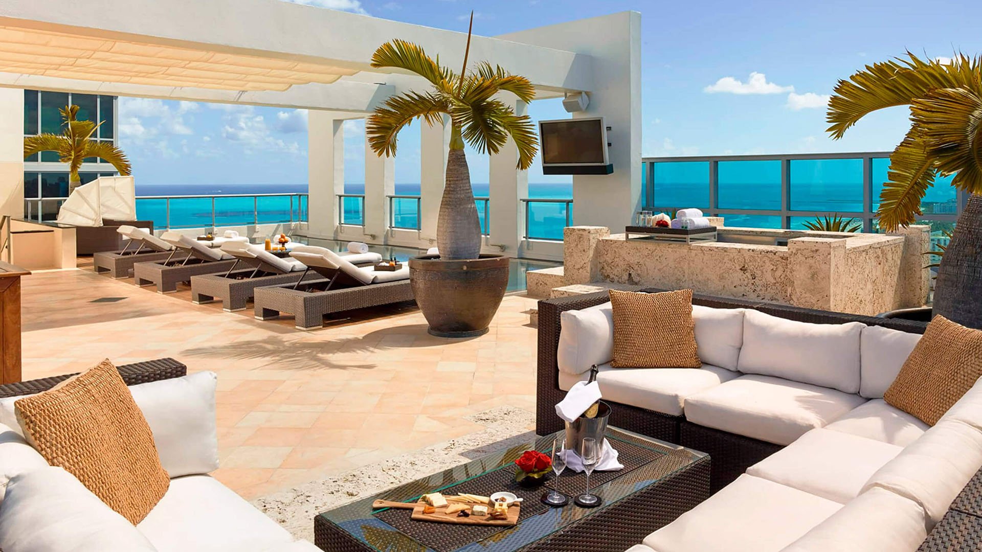 Ocean-view terrace lounge at Setai Miami Beach in Miami Beach featuring luxury and ultra luxury condos with pergola shade, sunbeds, outdoor seating, and expansive turquoise water views.