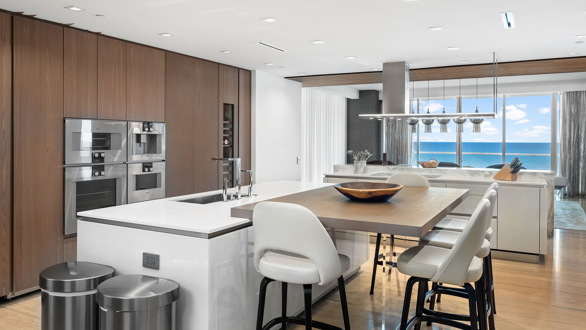 Turnberry Ocean Club in Sunny Isles Beach luxury and ultra luxury condos showcase a chef kitchen with breakfast bar seating, sleek cabinetry, and ocean views beyond.
